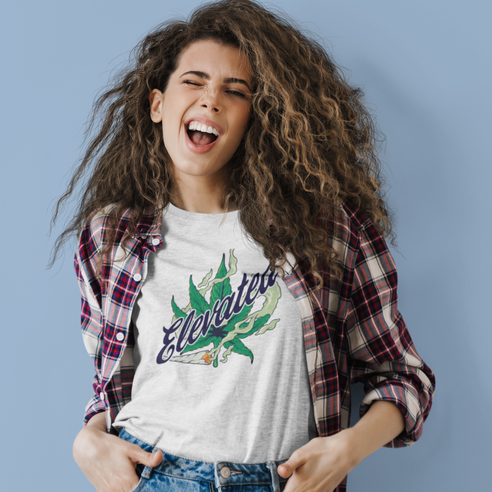 Woman wearing a white t-shirt with a graphic design and plaid shirt over it against a blue background