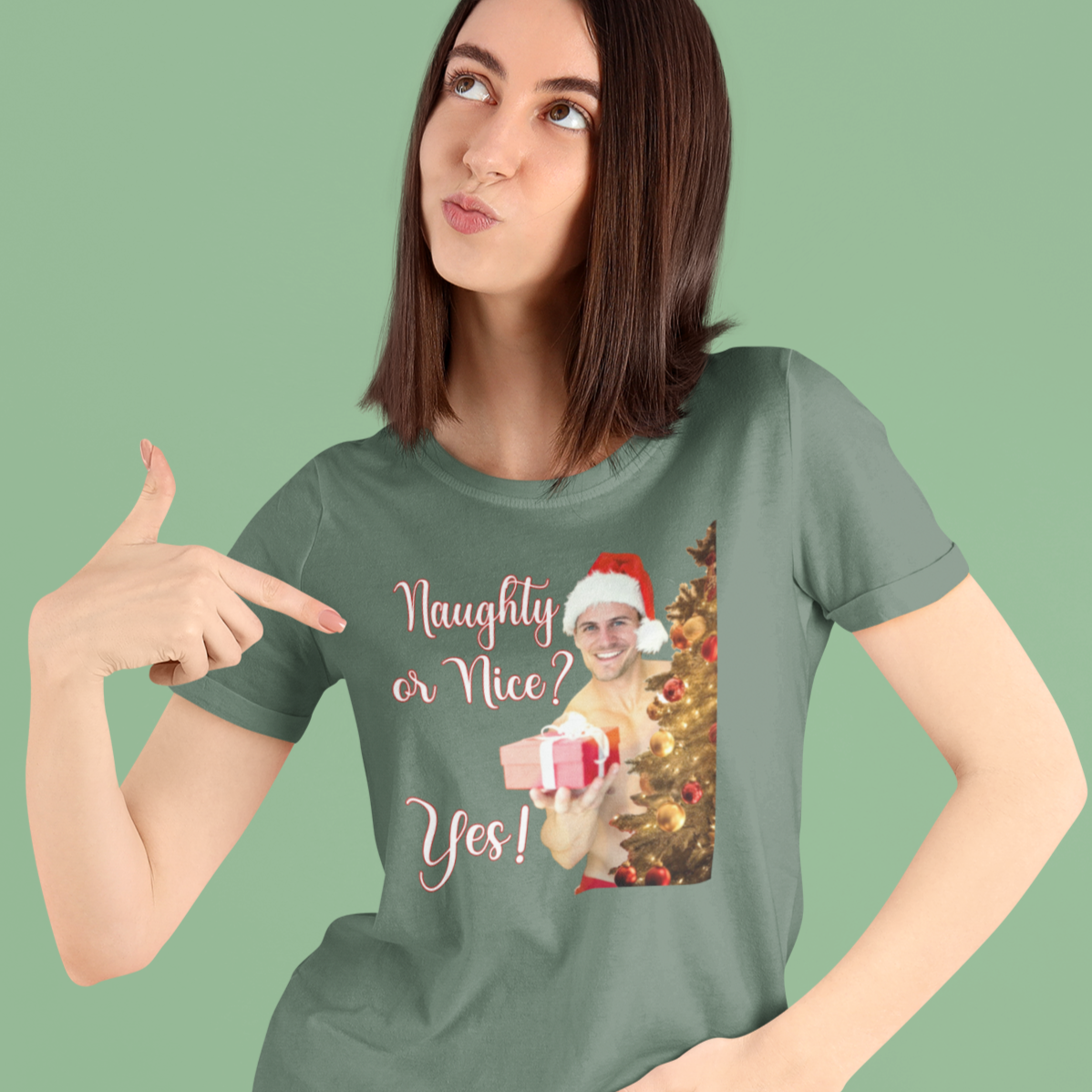 Woman wearing a green t-shirt with a Christmas-themed graphic and text, pointing to the shirt.