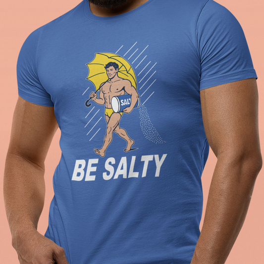 Blue t-shirt with a graphic of a man holding an umbrella and the text 'BE SALTY' on a peach background.