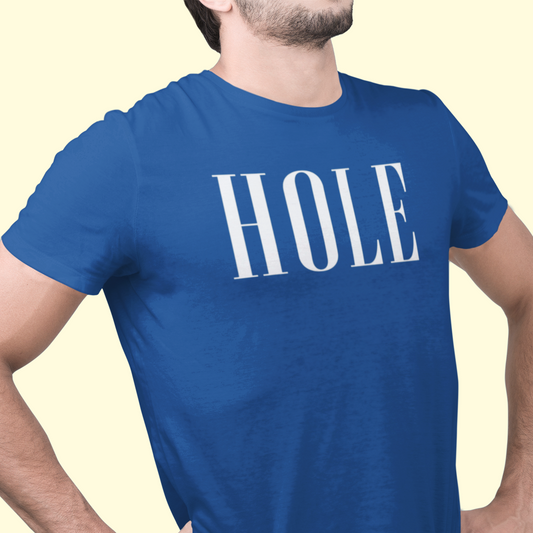 A man wearing a royal blue crewneck t-shirt with the word 'HOLE' printed in large white serif letters across the chest, posed against a solid pale yellow background.